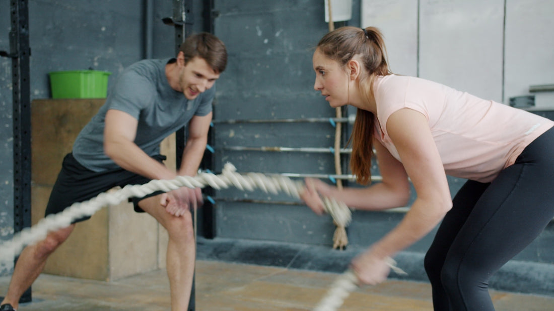 Man and woman exercising with battle ropes.